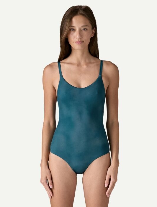 Person wearing a teal one-piece swimsuit, standing against a plain light background.
