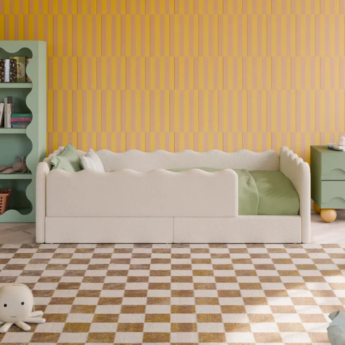A children’s bedroom with a white wavy-edged bed, green bedding, yellow striped wallpaper, a green shelf, green nightstand, and a checkered rug; a plush toy sits on the floor.