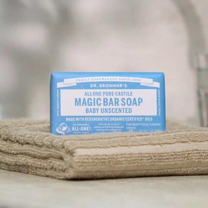 A bar of Dr. Bronner’s All-One Pure-Castile Magic Bar Soap (Baby Unscented) sits on a folded beige towel.