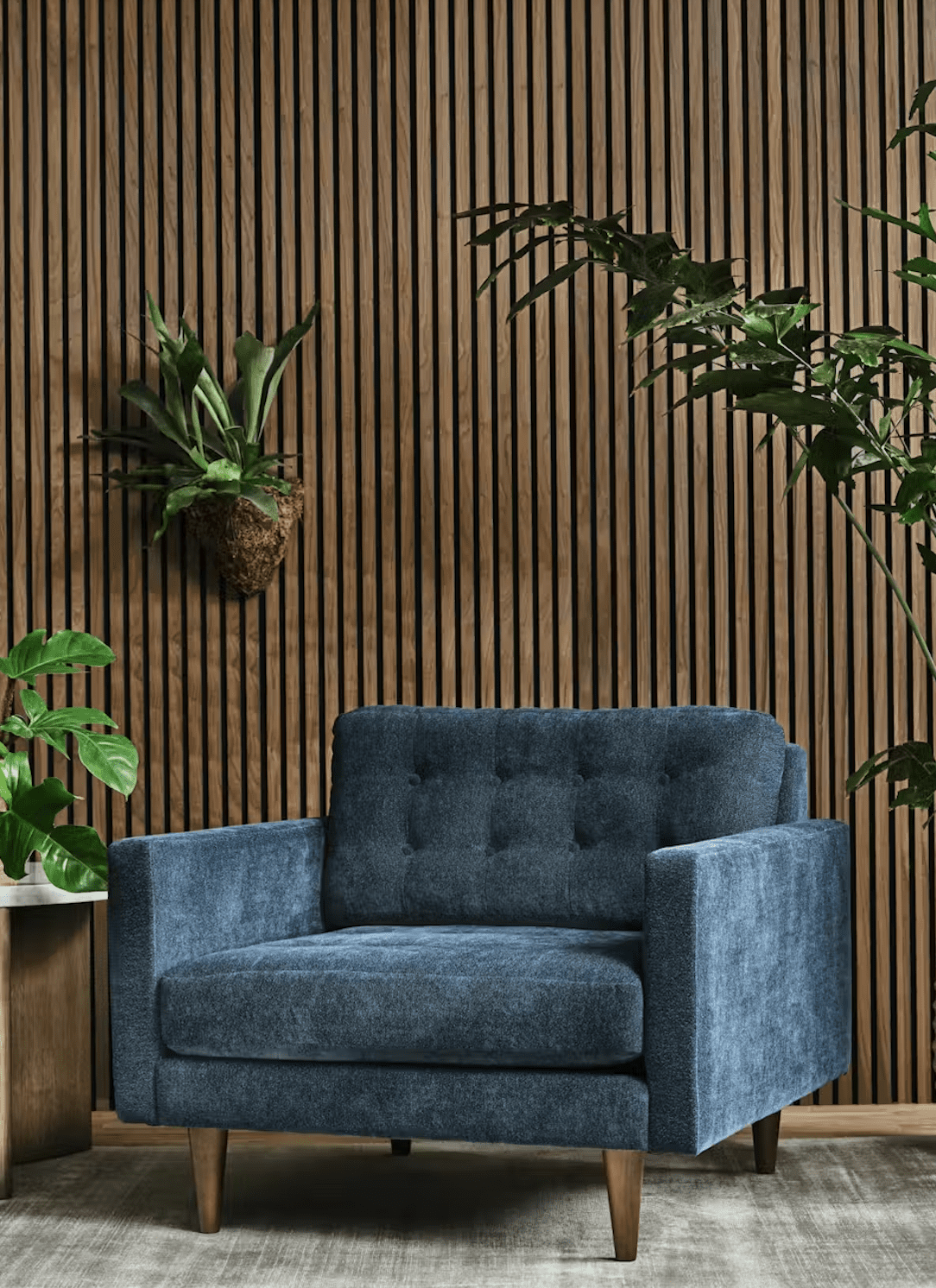 A blue upholstered armchair sits on a rug in front of a wooden slat wall, surrounded by various green indoor plants.