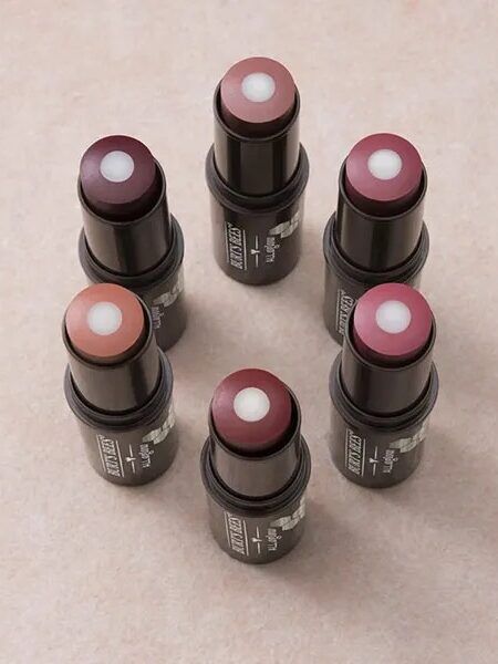Six tubes of lipstick, each with a different shade, arranged in a circular pattern on a neutral background.