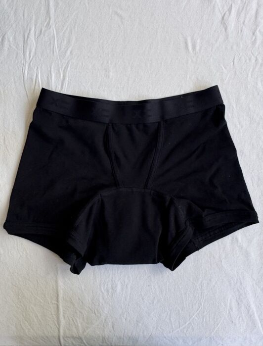 Black boxer briefs lying flat on a white surface.