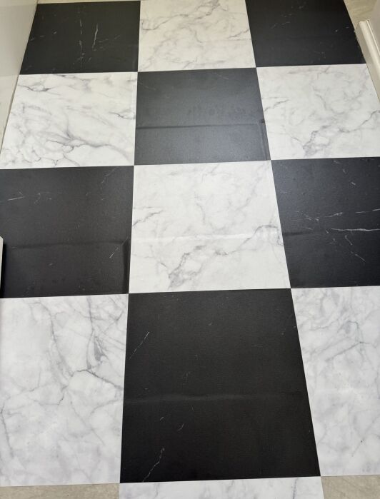 A black and white checkered floor with a marble pattern on the white tiles and a matte finish on the black tiles.