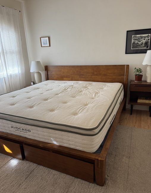 An Avocado Green Mattress on a wooden platform bed frame with built-in storage drawers.