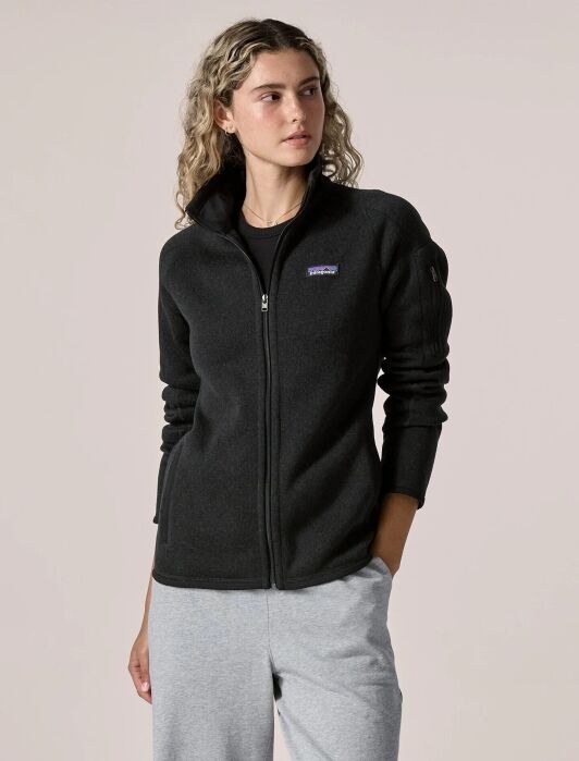 A person wears a black Patagonia full-zip fleece jacket over a black shirt and grey sweatpants.