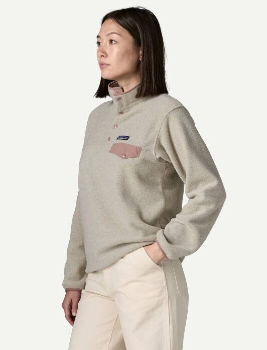 A person wears a beige fleece pullover with a snap-button placket and a chest pocket.
