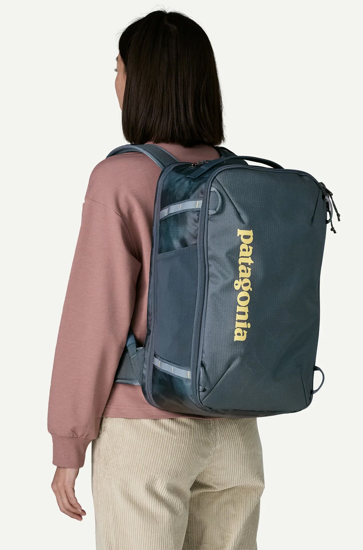 A person wearing a dark grey Patagonia travel backpack.