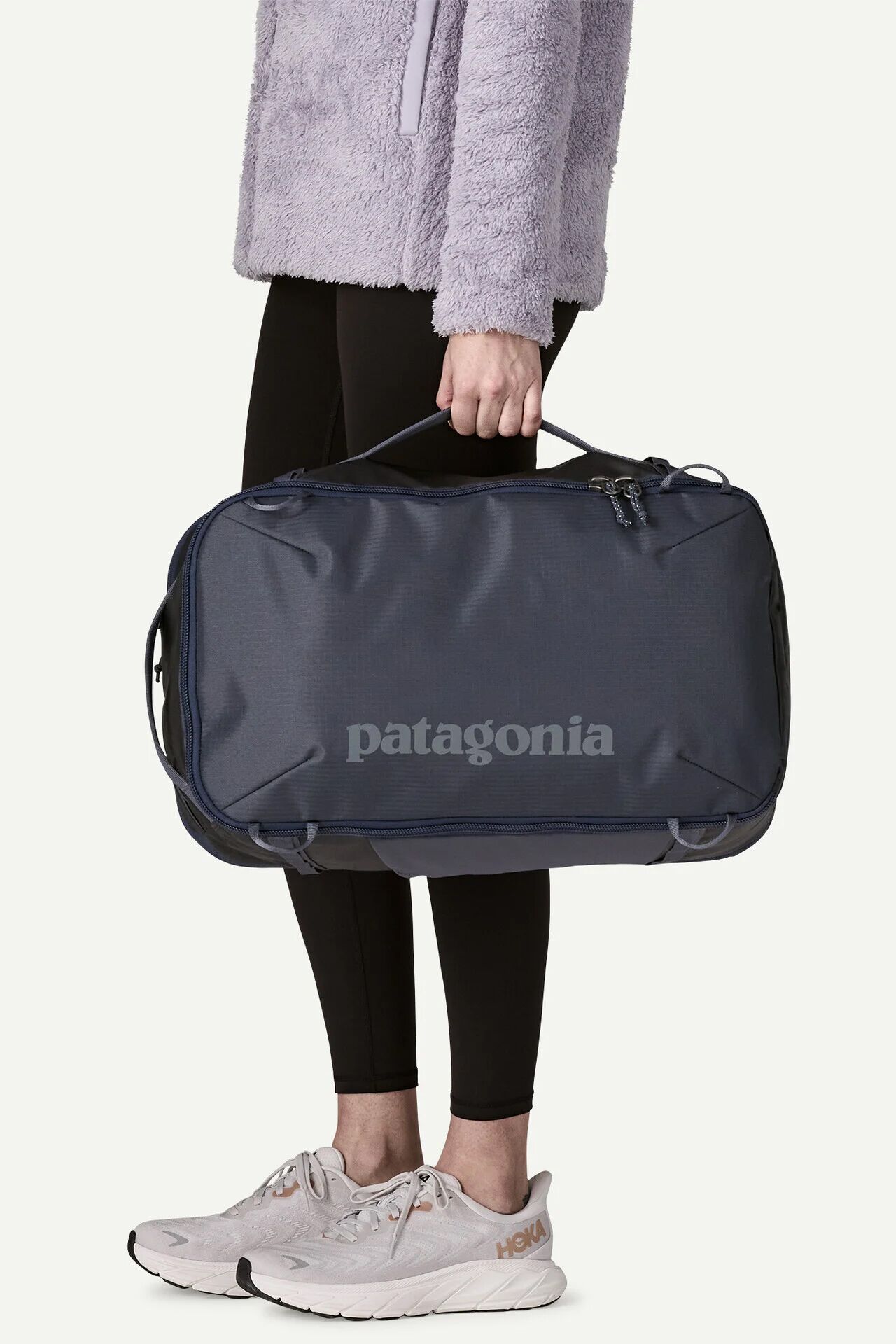 Person holding a dark blue Patagonia duffel bag by the top handle.