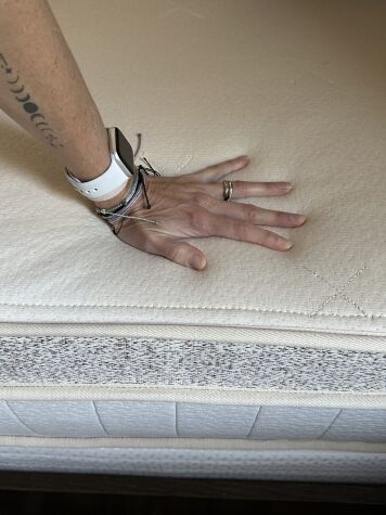 Hand pressing down on a Birch mattress.