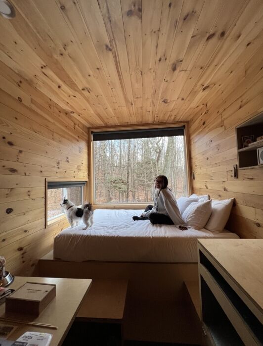 The writer and her dog sit on the queen sized bed and look out the large picture window.