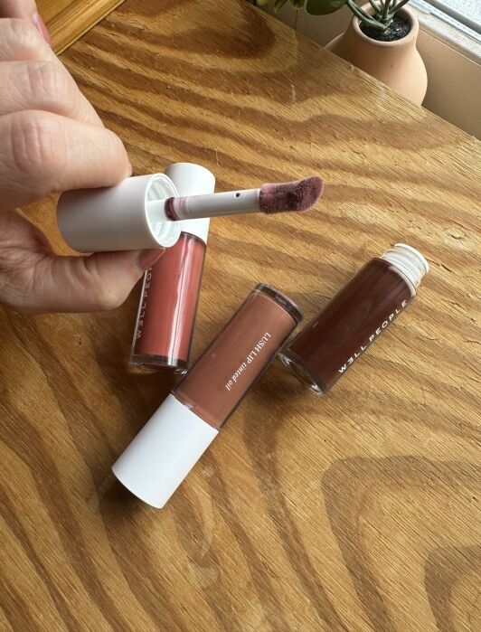 A person is putting lipstick on a wooden table.