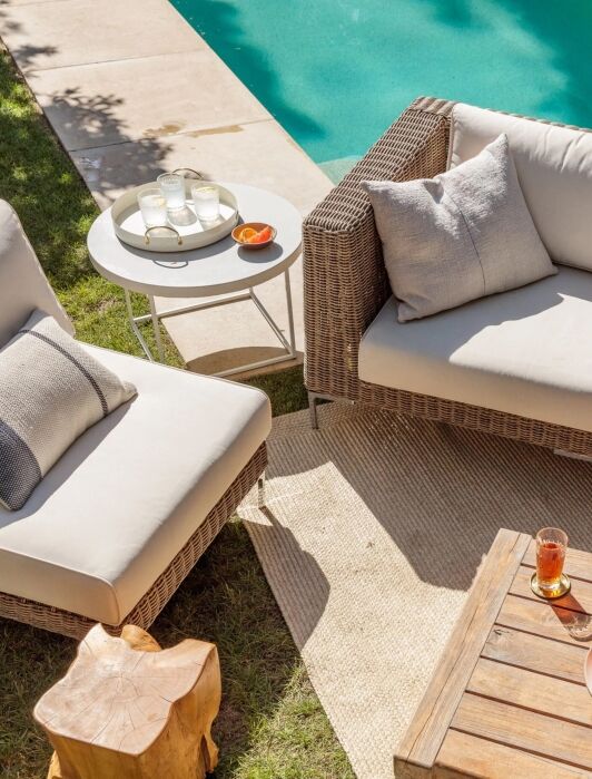 A set of wicker furniture next to a pool.