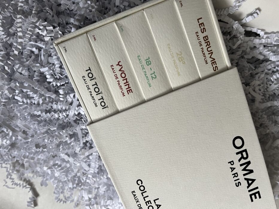 A box of Ormaie Paris perfume collection with sample bottles labeled Toï Toï Toï, Yvonne, 18-12, and Les Brumes, surrounded by shredded paper packaging.