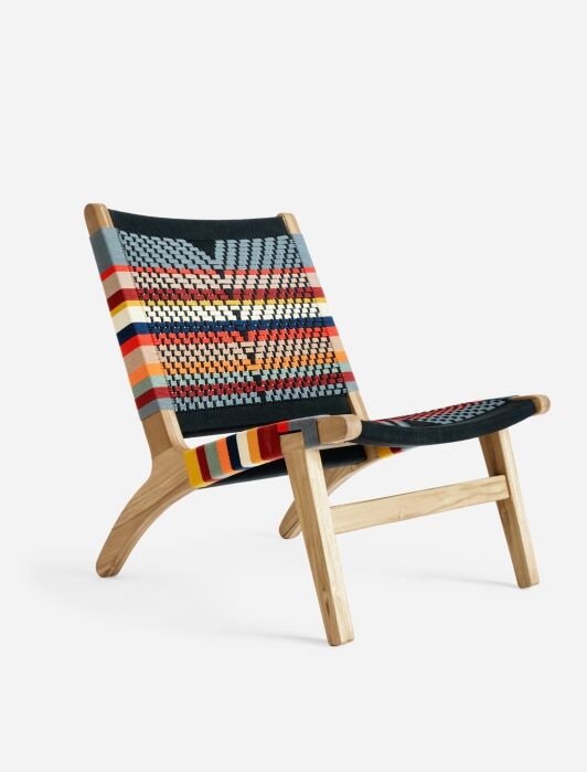 A handwoven lounge chair with a yellow, red, orange, blue and white woven pattern from MasayaCo. 