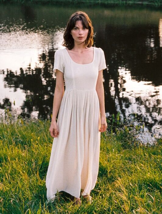 A model wearing a white square-neck maxi dress from Christy Dawn.