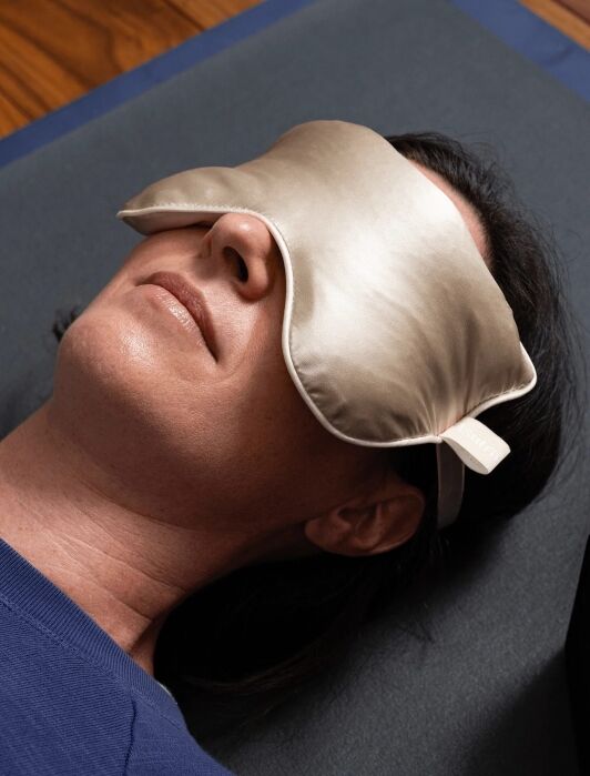A model laying down wearing an Asutra sleep mask.