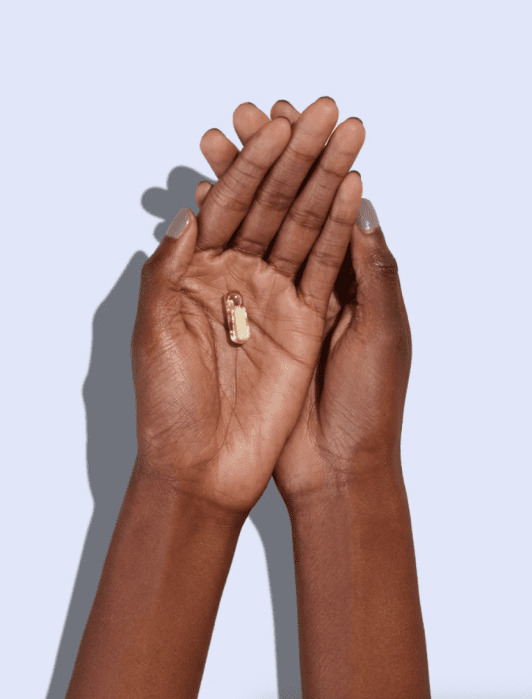 Two hands cupping a small golden zipper pull against a light background.