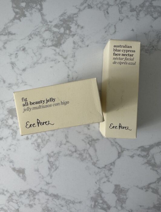 Two small boxes on a marbled surface; one labeled "fig all-beauty jelly," the other "australian blue cypress face nectar." Both have "Ere Perez" in script.