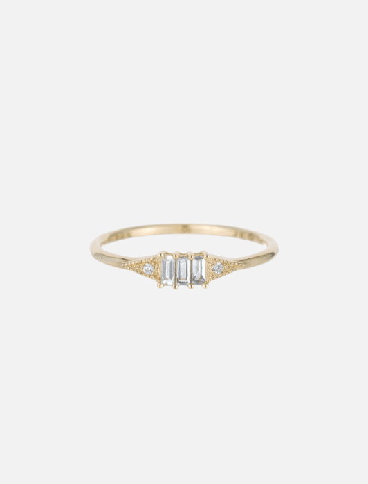 A gold ring with three rectangular diamonds in the center and small round diamonds on each side.