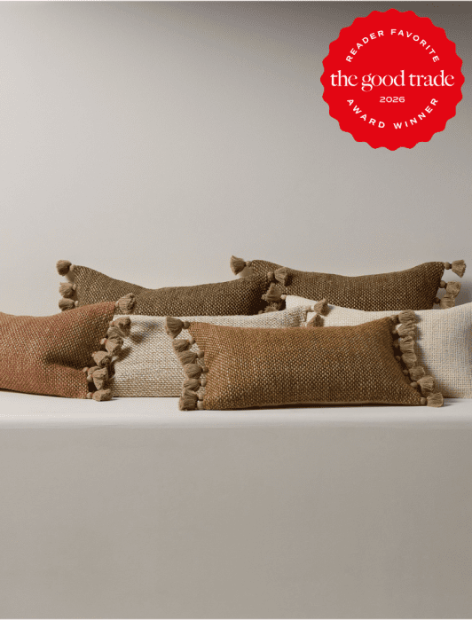 Four rectangular throw pillows in earthy tones with tassels are arranged on a white surface; a red "The Good Trade 2026 Award Winner" badge is in the top right corner.