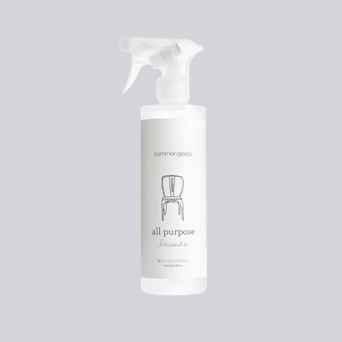 A clear spray bottle labeled "Common Good all purpose lavender" cleaner, with an illustration of a chair on the front, against a light gray background.