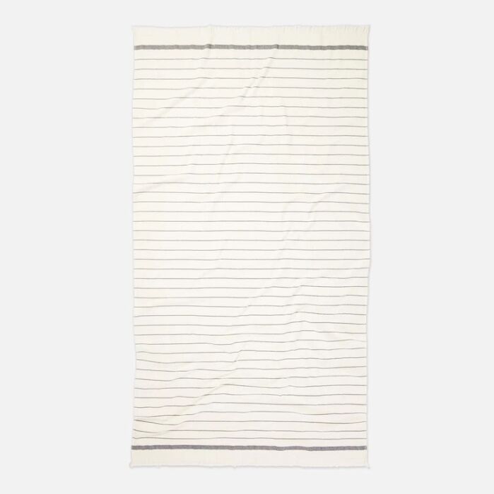 A cream-colored rectangular blanket with thin horizontal black stripes and thicker black borders on the top and bottom edges.