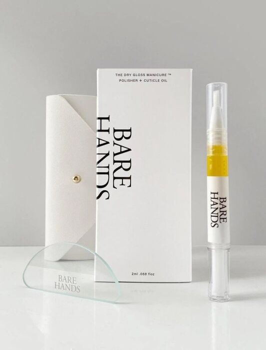 A manicure kit including a white case, a glass nail tool, a polisher and cuticle oil pen, and a white product box labeled "Bare Hands" on a plain surface.