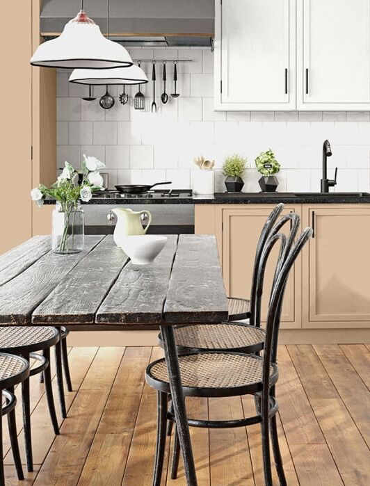 Modern kitchen with beige cabinets, black countertops, a rustic wooden dining table, six chairs, and potted plants on the counter and table.