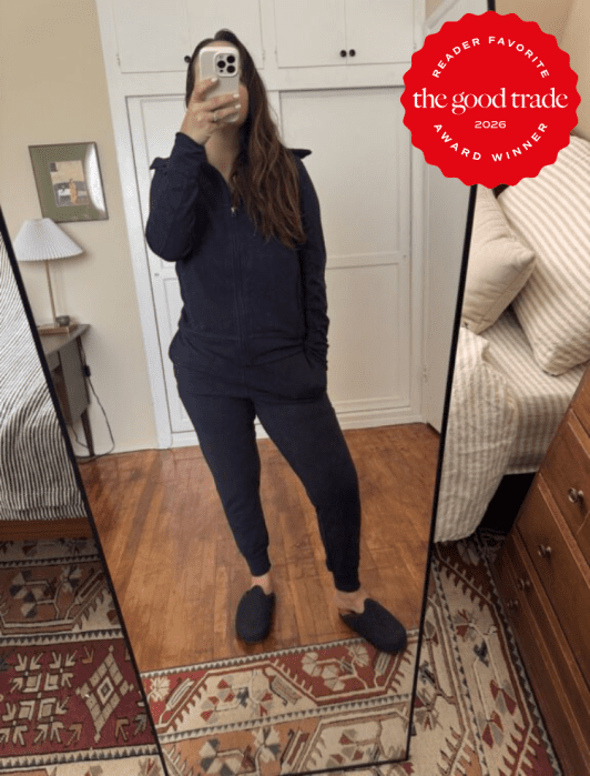 Person taking a mirror selfie in a bedroom, wearing a dark tracksuit and slippers. A "The Good Trade 2026 Award Winner" badge is overlaid in the top right corner.