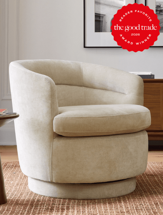A beige swivel chair on a brown textured rug, next to a wooden cabinet. A "The Good Trade Award Winner 2026" badge is in the top right corner.