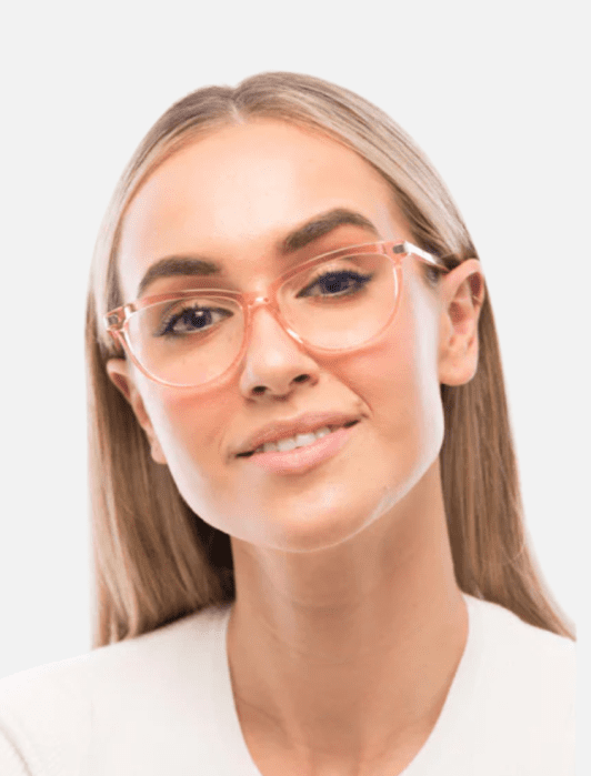 Woman with long straight blonde hair, wearing clear pink eyeglasses and a white top, smiles at the camera against a light background.
