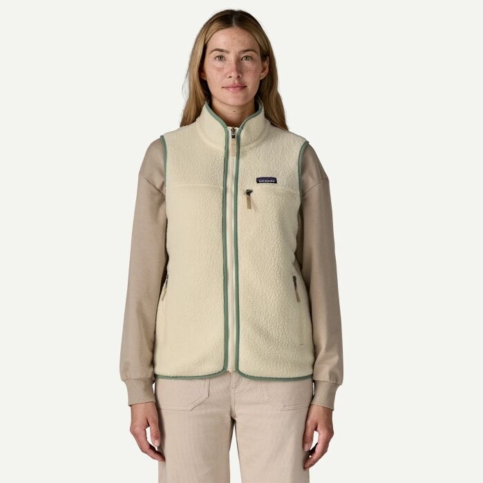 A person wearing a light beige fleece vest over a long-sleeve shirt and pants, standing against a plain background.