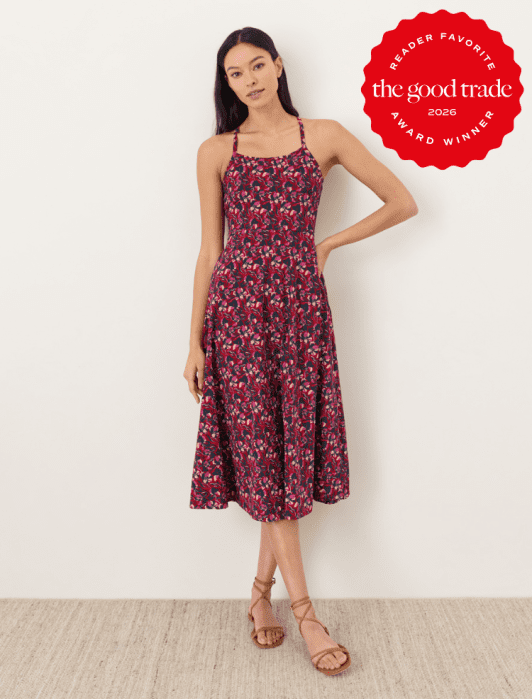 Woman wearing a sleeveless, floral-patterned midi dress stands against a white wall. A red badge reads "The Good Trade Reader Favorite Award Winner 2026.