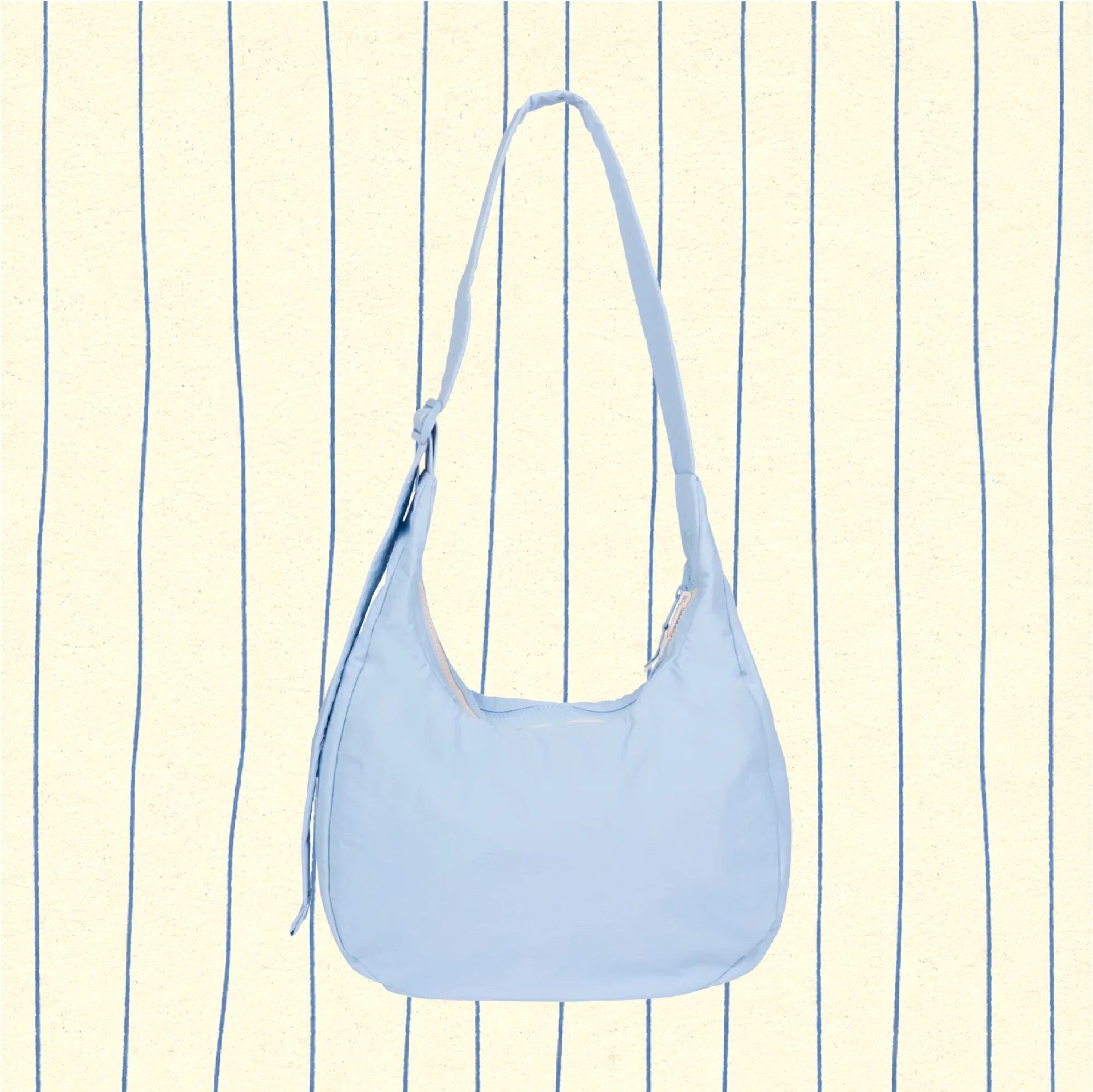 Light blue shoulder bag with a zipper, displayed against a cream background with vertical blue lines.