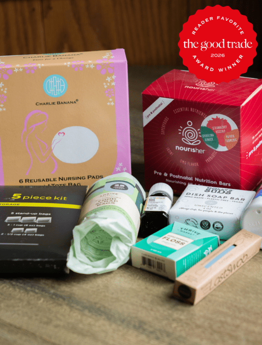 A selection of maternity and postpartum care products, including nursing pads, nutrition bars, a perineal spray, and other personal care items, displayed on a wooden surface.