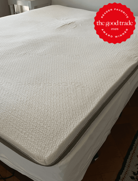 A neatly made mattress with a textured white cover on a bed frame, featuring a red "The Good Trade 2026 Reader Favorite Award Winner" badge in the top right corner.