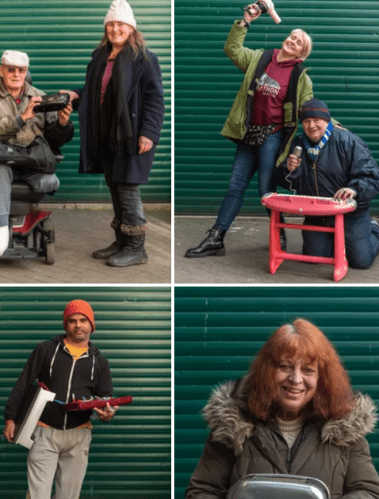 Four pairs and individuals stand in front of a green corrugated wall, each holding household items like a hair dryer, radio, lamp, and sewing machine.