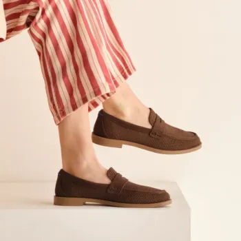 Person wearing red and white striped pants and brown loafers stands on a white platform against a plain beige background.