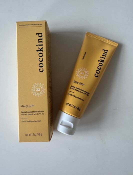 A yellow tube and box of Cocokind daily SPF 32 facial sunscreen lotion with broad spectrum UVA/UVB protection, 1.7 oz size, displayed on a white surface.