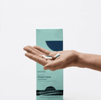 A hand holds several capsules in front of a teal box labeled “Power Pack” by bird&be, a male fertility support supplement.