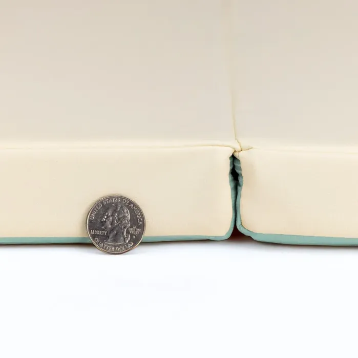 A U.S. quarter coin is placed upright in front of the seam between two cream-colored foam pads with a light green base.