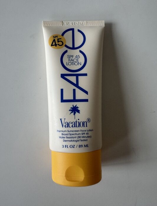A tube of Vacation brand SPF 45 face lotion sunscreen, 3 fl oz (89 ml), with a yellow cap, photographed on a plain surface.