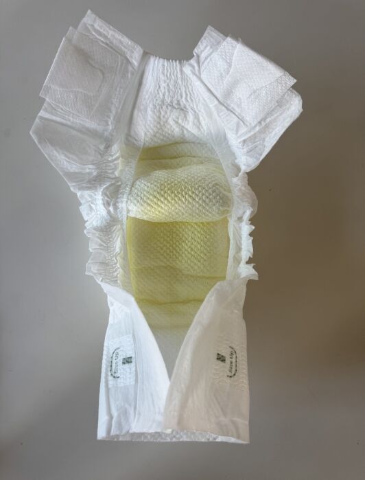 An open disposable diaper shows a yellow stain in the absorbent area, indicating it has been used.
