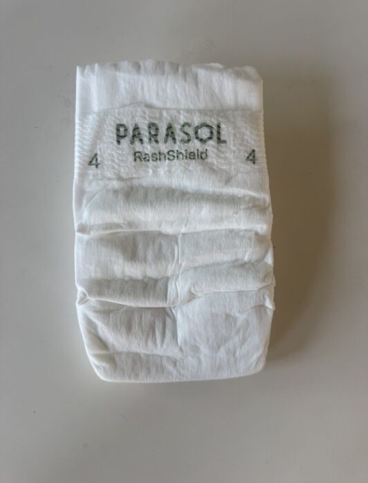 A single white Parasol RashShield size 4 diaper is placed on a plain, light-colored surface.