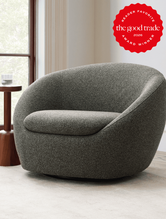 A gray upholstered, rounded armchair sits on a light rug near a window; a red award badge in the corner reads "The Good Trade 2026 Award Winner, Reader Favorite.