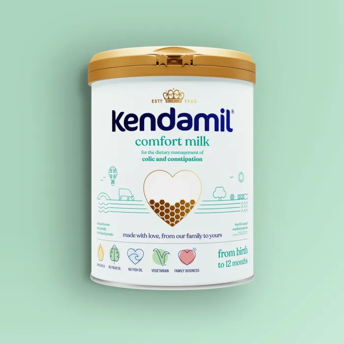 A can of Kendamil Comfort Milk formula for infants, labeled for colic and constipation, with a gold lid and light blue-green background.