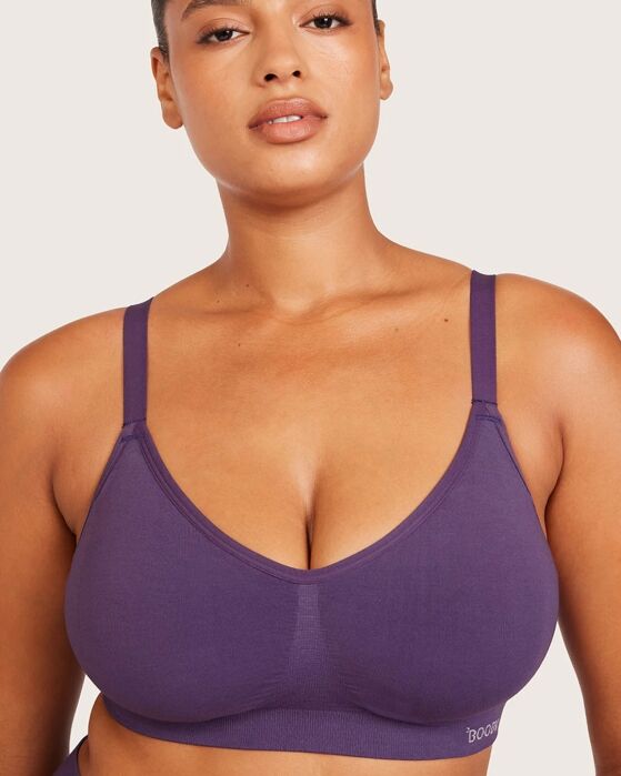A person wearing a purple seamless bralette, posing against a plain light background.
