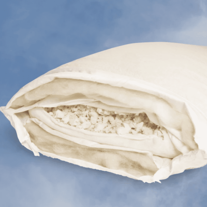 A cross-section of a white pillow shows shredded filling and inner layers against a light blue background.