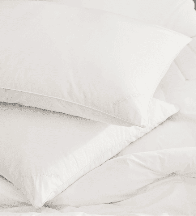 Two white pillows stacked on a white comforter, all with a smooth and clean appearance.
