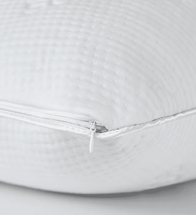Close-up of a white cushion with a textured fabric surface and a partially visible zipper along one edge.